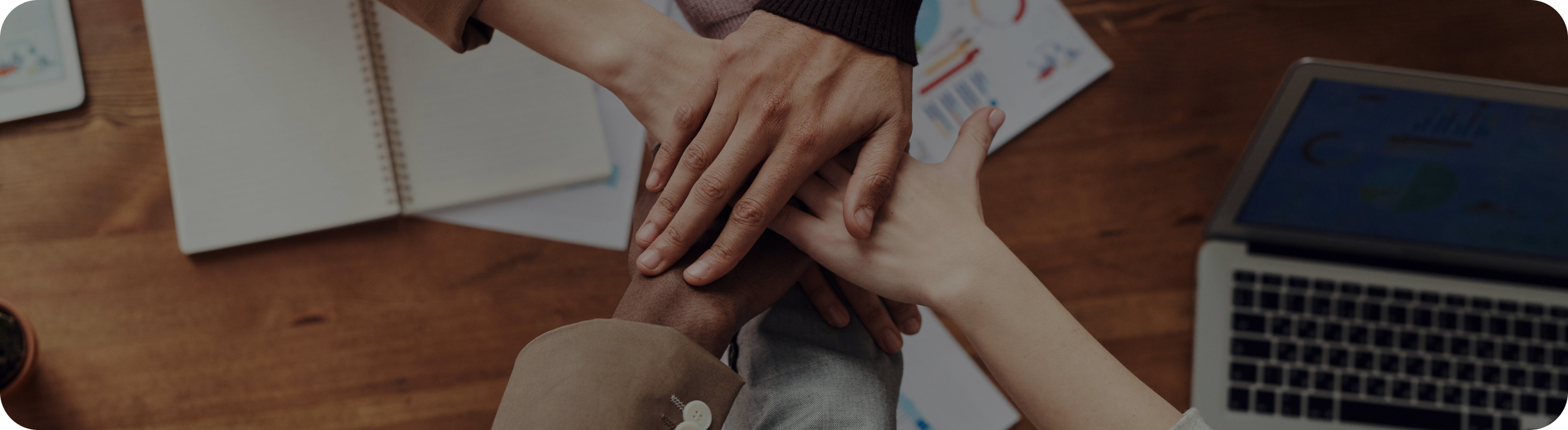 Partners stacking hands over a work table